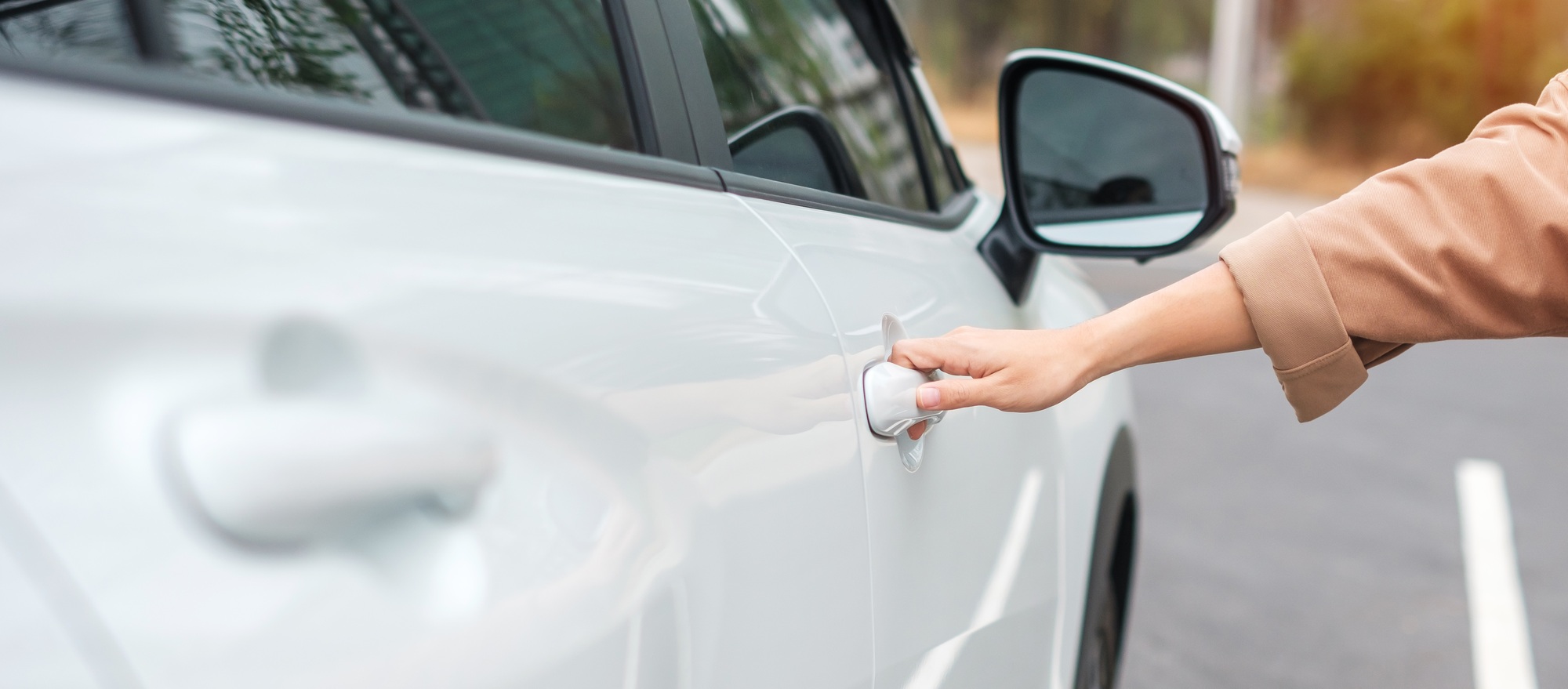Hand holding smart car handle and opening a door. Transport, travel, service and car rental concept